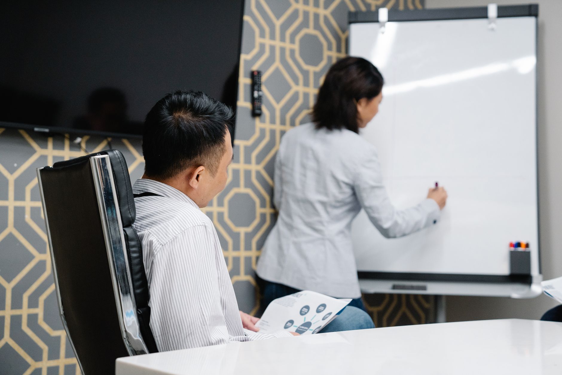 Des professionnels participent à une réunion collaborative en utilisant un tableau blanc pour le brainstorming.